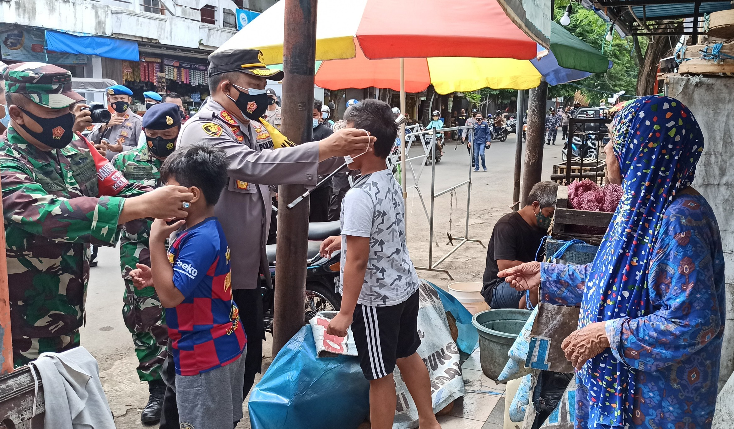 Kapolresta Banyuwangi Kombespol Arman Asmara Syarifuddin dan Dandim 0825 Banyuwangi memasangkan masker pada dua orang  anak-anak. (Foto: Muh Hujaini/Ngopibareng.id) 