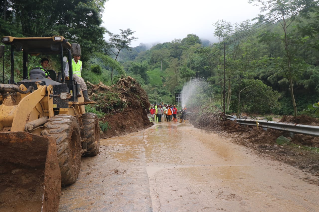 Para petugas dibantu alat berat saat membersihkan material longsor yang memenuhi badan jalan di Dusun Jombok, Ngantang, Kabupaten Malang, Jawa Timur. (Foto: Istimewa)