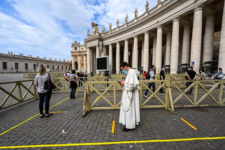 Warga maupun rohaniwan berbaris rapi mengikuti aturan pembatasan sosial untuk memasuki Basilika Santo Petrus di Vatikan. (Foto: AFP/VOCENZO PINTO)