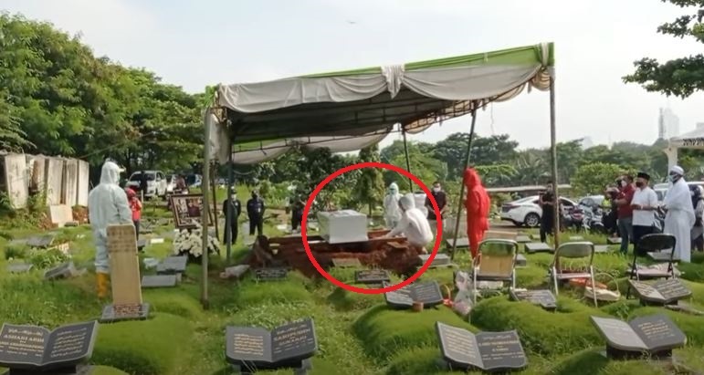 Teddy Syah memakai alat pelindung diri (APD) lengkap saat mengadzani jenazah sang istri, Rina Gunawan, di dalam peti mati. Prosesi pemakaman di TPU Tanah Kusir, Jakarta, Rabu 3 Maret 2021. (Foto: Istimewa)