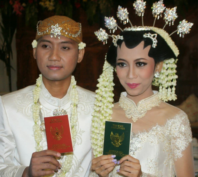 Sepasang pengantin dengan bangga memperlihatkan buku nikah yang baru diterima dari petugas pencatat nikah, setelah membacakan ijab kabul, dijamin asli. (Foto: Asmanu/Ngopibareng.id)