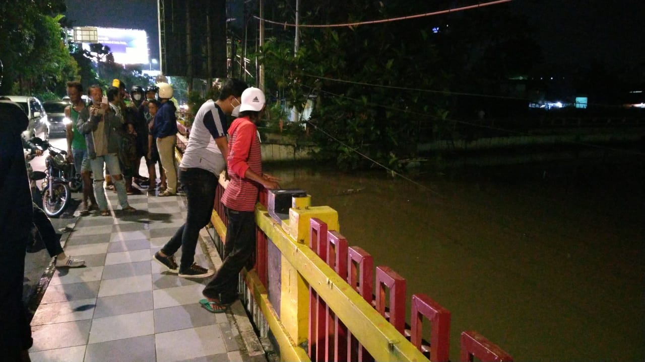 Warga mencoba mencari jejak korban yang tenggelam di Kali Jagir, Surabaya, Sabtu 20 Maret 2021 malam. (Foto: Fariz Yarbo/Ngopibareng.id)