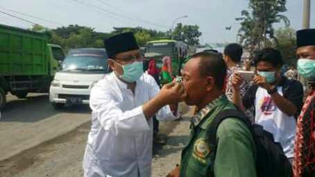 Wakil Gubernur Jatim Saifullah Yusuf memasangkan masker kepada pengguna jalan, Gresik, Minggu (12/3). (Foto: Wah)