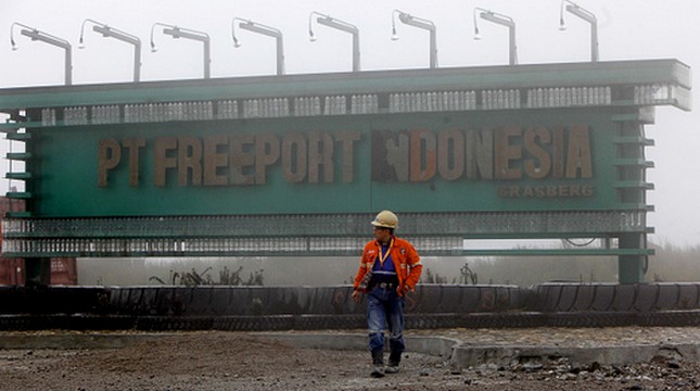 PEMANGKASAN: Seorang pekerja di depan papan nama PT Freeport di Papua. 