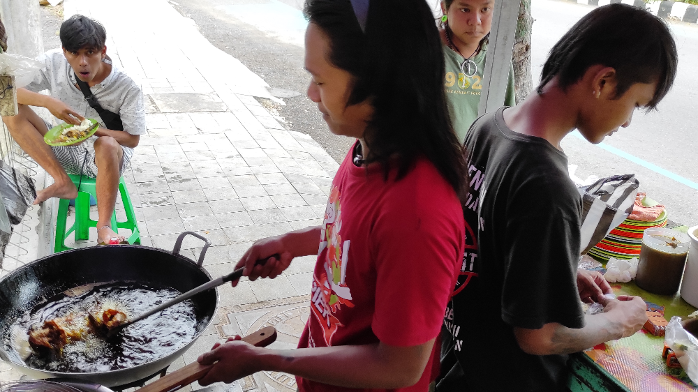 Sega, satu dari lima anak punk, sedang melayani pembeli sambal penyetan. (Foto: Fendhy Plesmana/Ngopibareng.id)