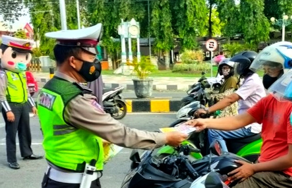 Anggota Satlantas Polres Situbondo membagikan brosur imbauan larangan Mudik Lebaran 2021 kepada pengendara di jalan. (foto humas polres)