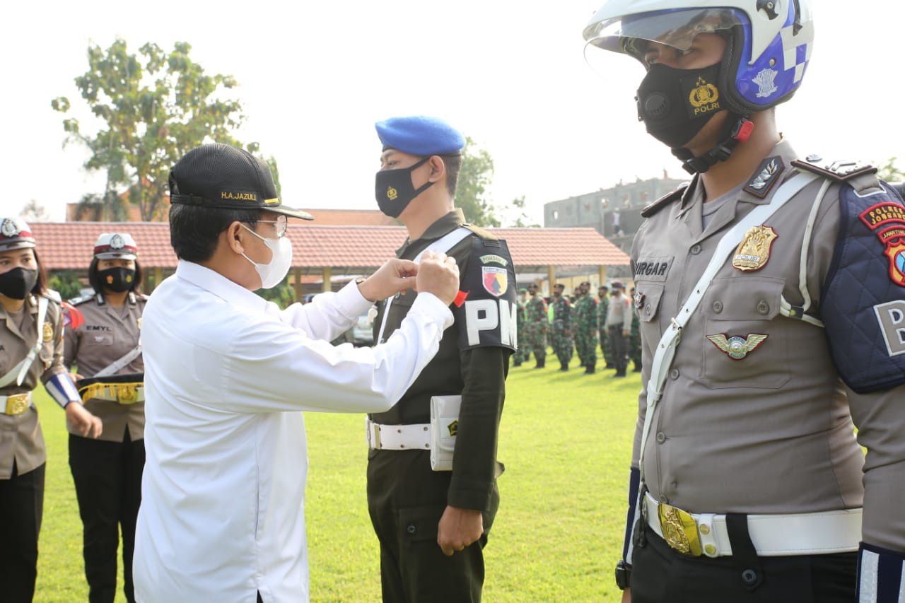 Sekdakab Jombang Akhmad Jazuli memasang pita kepada salah satu anggota Subdenpom V/2 Jombang dan Satlantas Polres Jombang. (Foto: Istimewa)