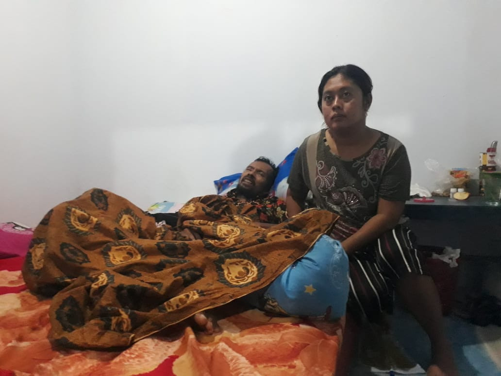 Nur Rockhim ditemani istrinya di rumah. Ia menderita lumpuh setelah mendapat suntikan vaksin covid-19. (Foto: Choirul Anam/Ngopibareng.id)