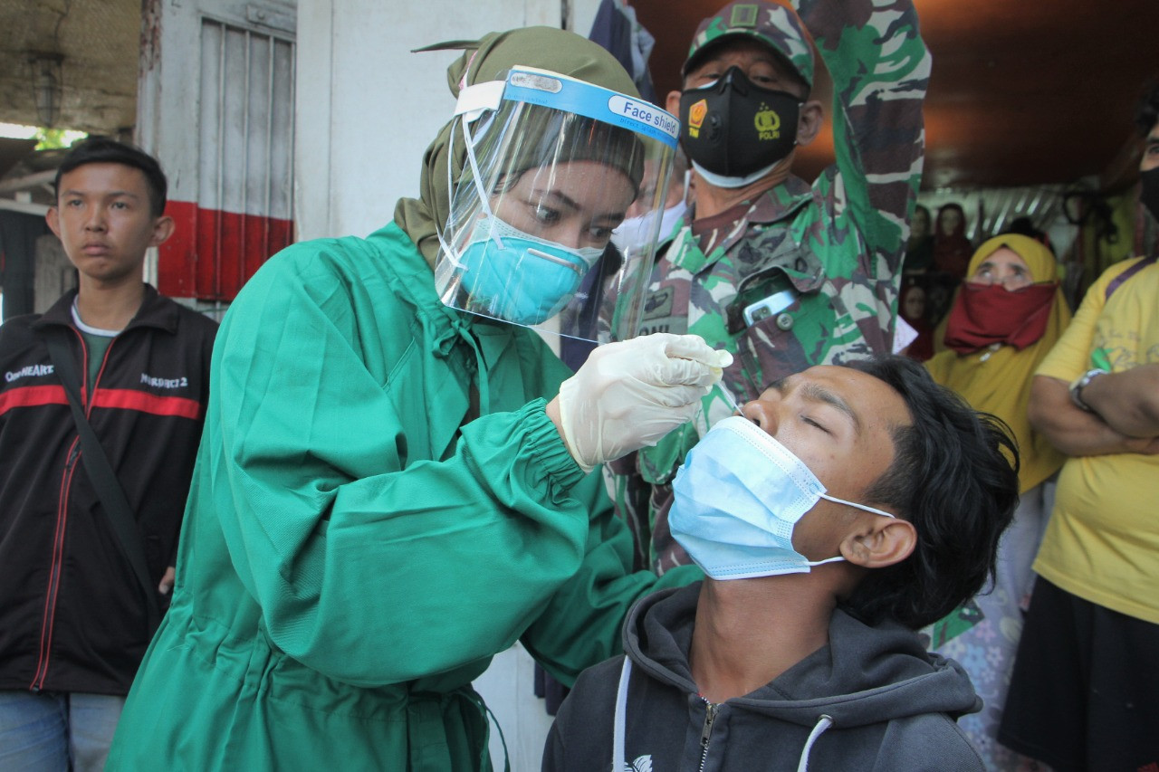 Pembeli tidak bermasker yang terjaring razia, diberi masker kemudian di tes swab. (Foto: Ikhsan Mahmudi/Ngopibareng.id)