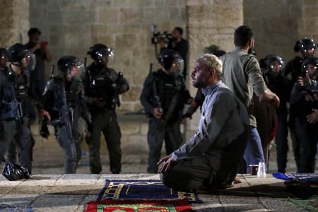 Seorang Muslim warga Palestina saat salat di Masjid Al-Aqsha, dan polisi Israel sebelum terjdi bentrok saat bulan suci puasa Ramadhan. (Foto: reuters)