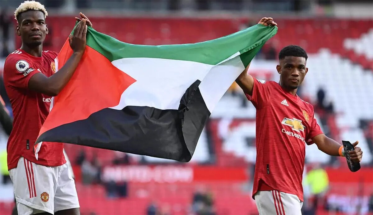 Gelandang Manchester United Paul Pogba (kiri) dan Amad Diallo mengibarkan bendera Palestina sebagai bentuk dukungannya. (Foto: AFP)