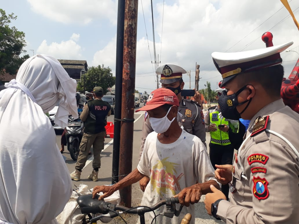 Seorang pengendara sepeda pancal mendapat teguran dari petugas karena tidak memakai masker. (Foto: Choirul Anam/Ngopibareng.id)