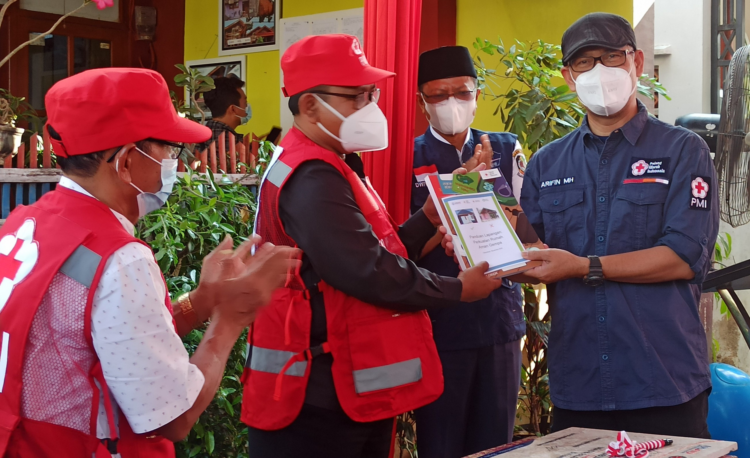 Kepala Bidang Penanggulangan Bencana Markas PMI Pusat Arifin M Hadi menyerahkan buku panduan rumah tahan gempa kepada Wakil Bupati Banyuwangi Sugirah. (Foto: Muh Hujaini/Ngopibareng.id)