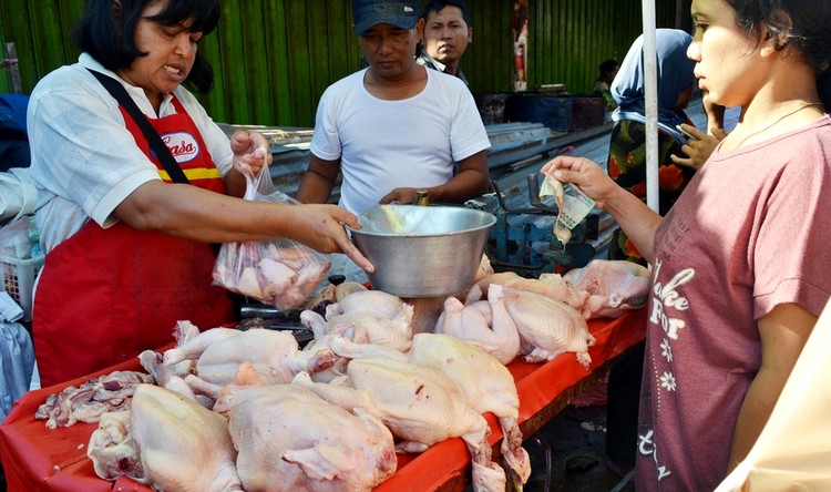 Ibu penjual daging ayam potong di pinggir jalan Kecamatan Bondowoso laris manis. (Foto: Guido Saphan/Ngopibareng.id)