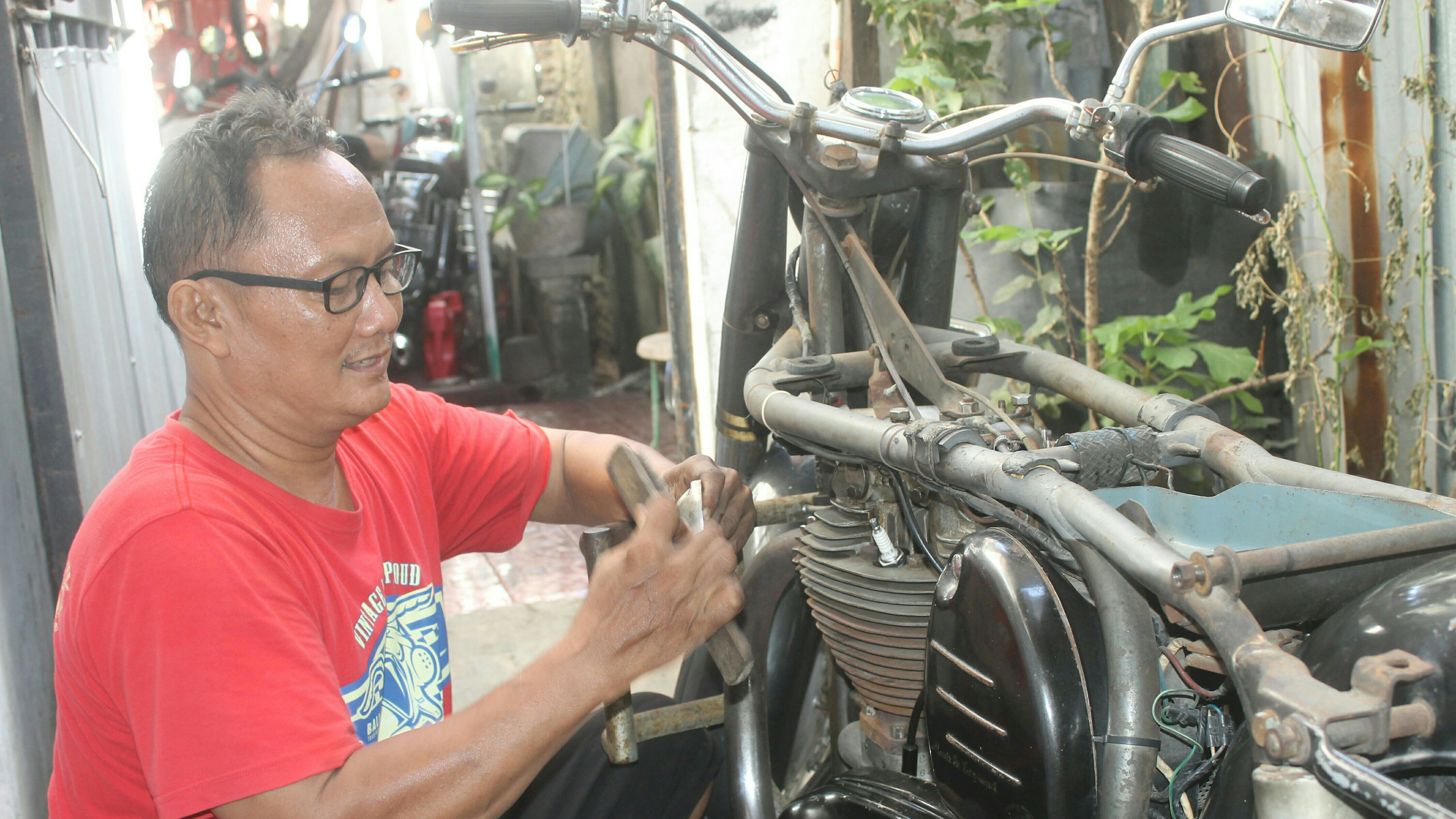 Zamroni dengan motor tua yang menjadi bagian dari hidupnya (foto: Asmanu Sudarsno/ngopibsreng.id)