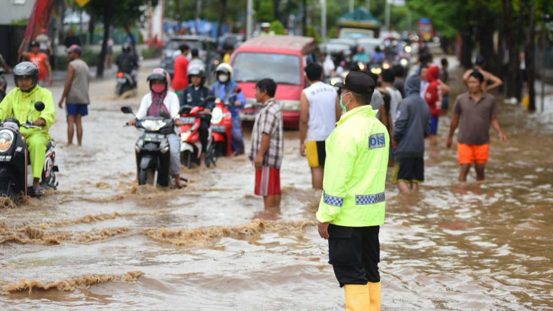 Kapolsek Banyuwangi AKP Kusmin mengatur lalu lintas di Jl. S. Parman saat terjadi genangan akibat meluaoknya sungai Bagong (foto:istimewa)