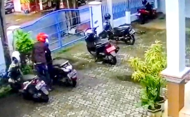 Pelaku mengenakan helm warna merah saat beraksi mencuri sepeda motor di halaman depan kantor Diskominfo Bondowoso. (Foto: Tangkapan layar rekaman CCTV kominfo)