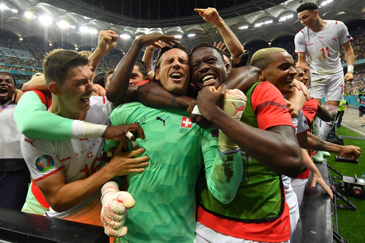 Kegembiraan para pemain Swiss merangkul kipernya usai berhasil menyelamatkan tendangan Mbappe yang sekaligus mencatatkan Swiss melaju ke babak semifinal Euro 2020. (Foto: AP Photo)