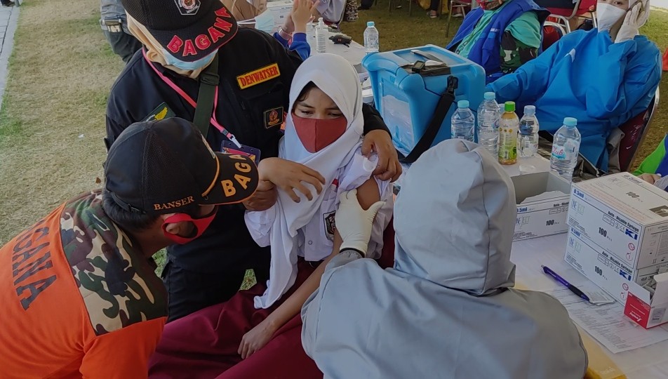 Relawan dan nakes membujuk Siswi SDN Pacar Kembang 1, Salma Feriansyah, yang takut saat hendak menjalani vaksinasi di Stadion Gelora 10 November, Surabaya, Minggu 11 Juli 2021. (Foto: Fariz Yarbo/Ngopibareng.id) 