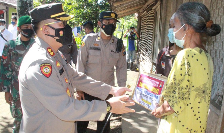 Kapolres Bondowoso AKP Herman Priyanto menyerahkan bantuan paket sembako kepada ibu-ibu terdampak Covid-19 di Desa Petung, Kecamatan Curahdami, Minggu 11 Juli 2021. (foto: guido/Ngopibareng.id)
