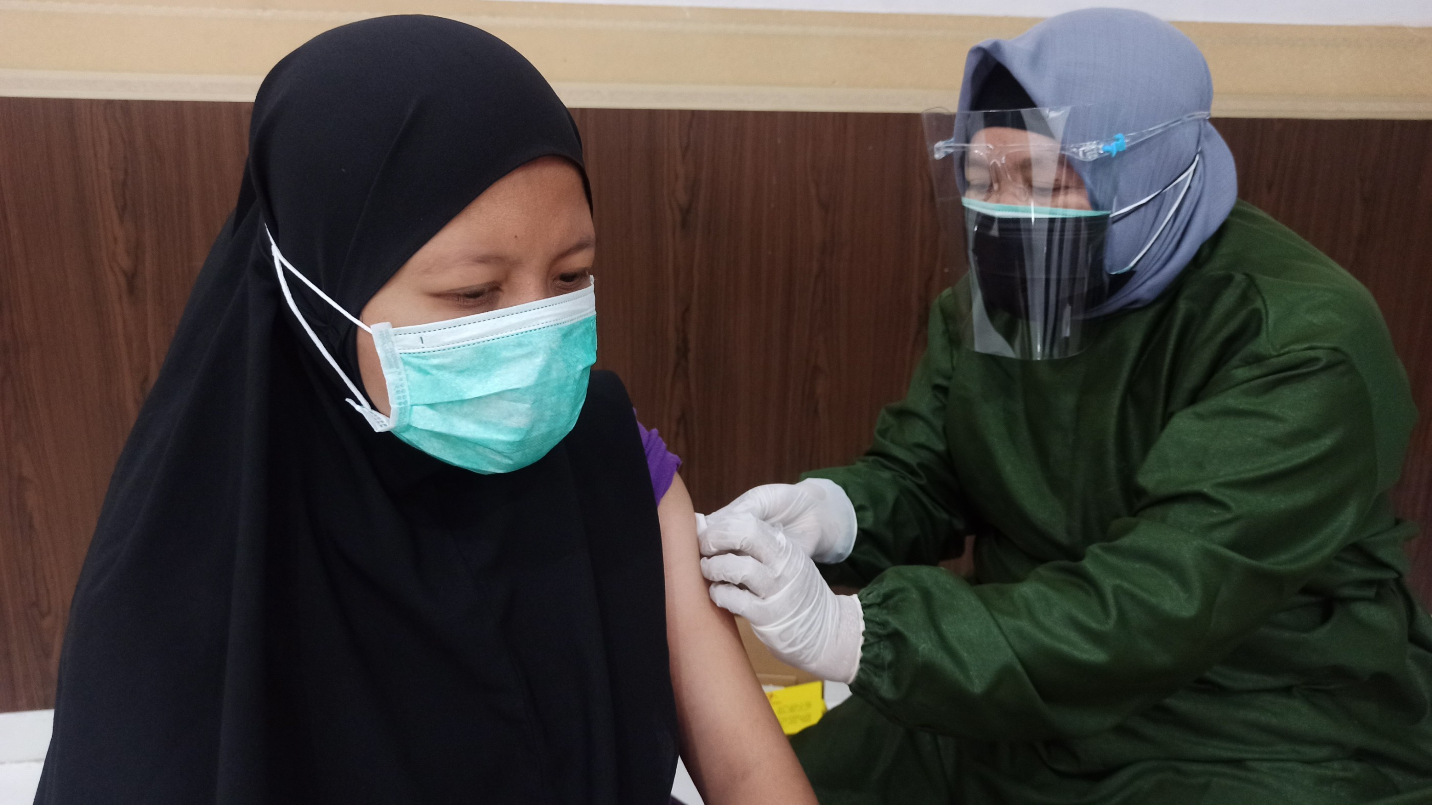 Petugas vaksinator menyuntikkan vaksin Covid-19 kepada salah seorang anak. (Foto: Muh Hujaini/Ngopibareng.id)