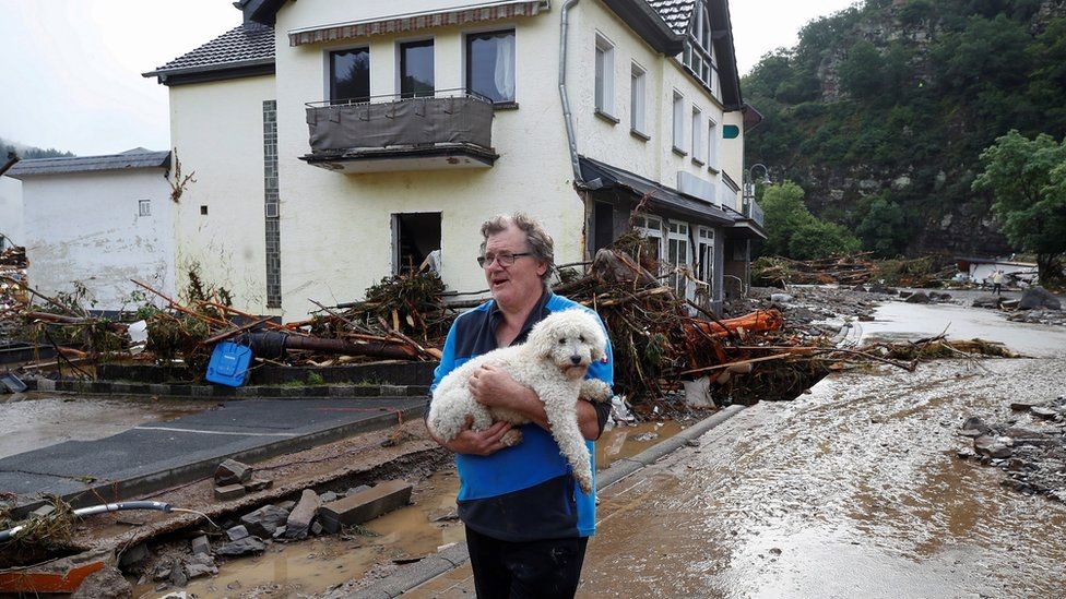 Seorang warga sedang membawa hewan kesayangannya selepas banjir di Jerman Barat. (Foto: bbc)