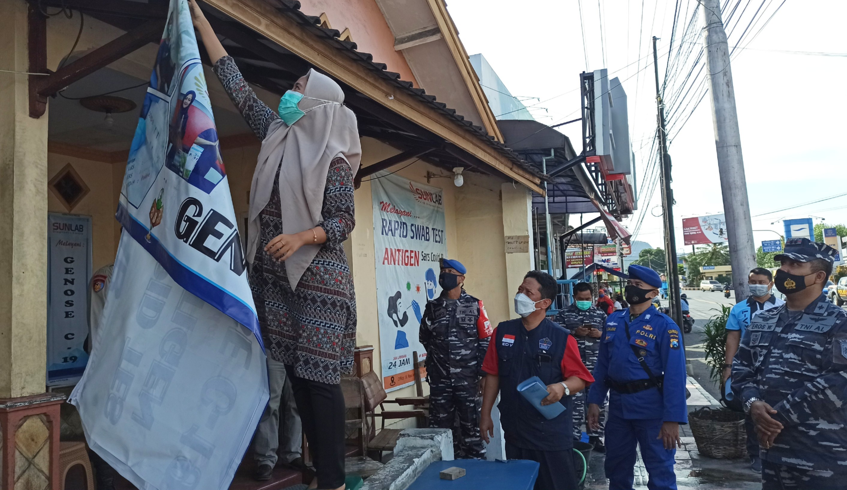 Petugas meminta salah satu klinik yang ada di area pelabuhan Ketapang untuk menutup praktik dan membuia papan namanya. (Foto: Muh. Hujaini/Ngopibareng.id)