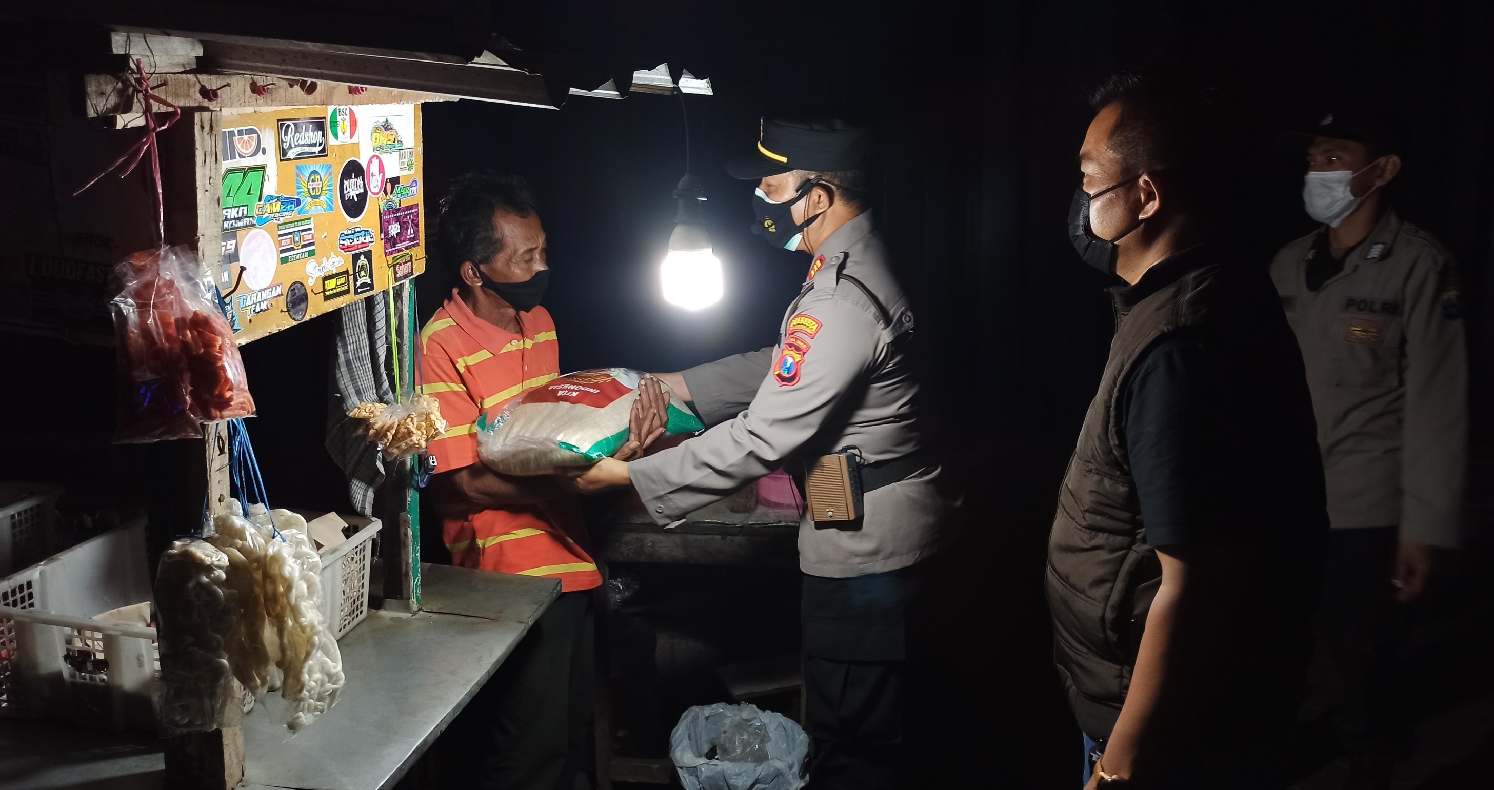 Petugas memberikan bantuan kepada pemilik warung kopi sembari mengingatkan peraturan PPKM Darurat (foto: Muh Hujaini/Ngopibareng.id)