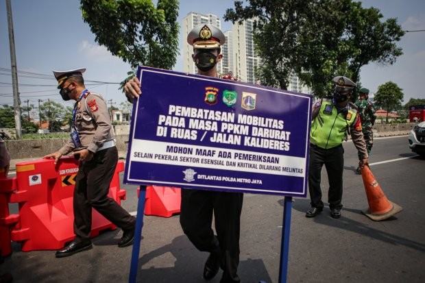 Petugas Kepolisian mengangkat papan informasi pembatasan mobilitas PPKM Darurat di pos penyekatan pembatasan menuju Jakarta di kawasan Kalideres, Jakarta, Minggu (4/7/2021). Polisi melakukan penyekatan di 63 titik wilayah di Jadetabek untuk membatasi mobilitas warga saat Pemberlakuan Pembatasan Kegiatan Masyarakat (PPKM) Darurat yang berlangsung hingga 20 Juli 2021. (Foto: Antara/Fauzan)
