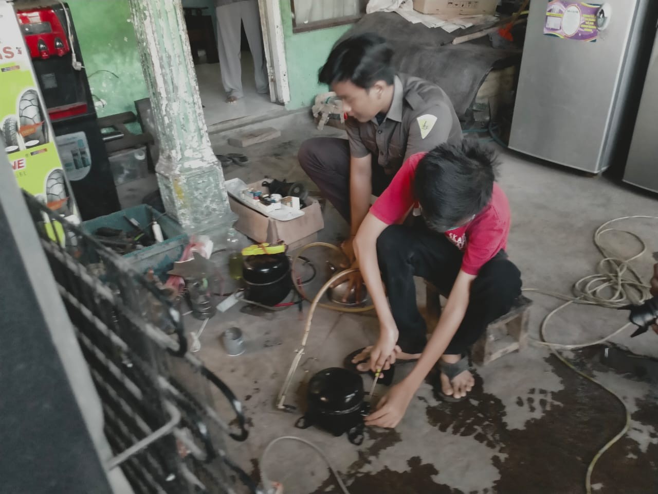 Adib Surya Ramadhan sedang menyervis mesin cuci di rumahnya Jalan Raya Bromo, Kota Probolinggo. (Foto: Ikhsan Mahmudi/Ngopibareng.id)