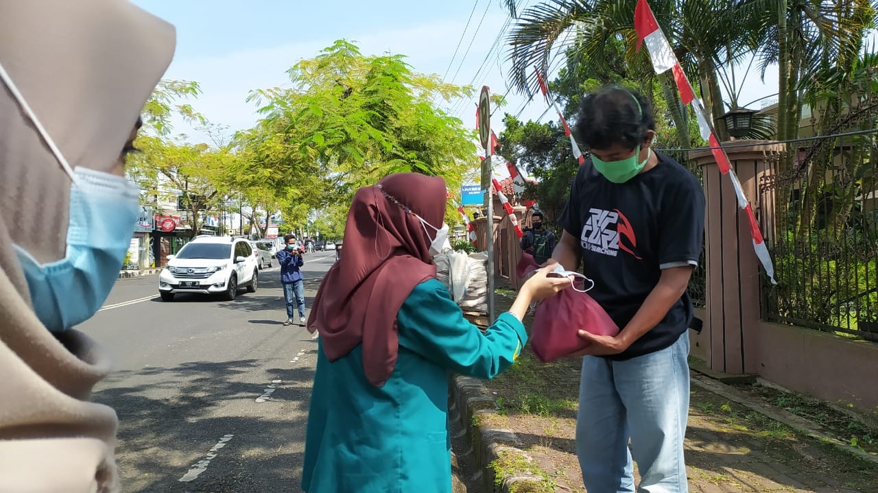 Seorang mahasiswa UIN Syaifuddin Purwokerto saat memberikan bantuan kepada masyarakat yang melintas di sekitar jalan rasa depan Pasar Manis Purwokerto. (Foto: Istimewa)