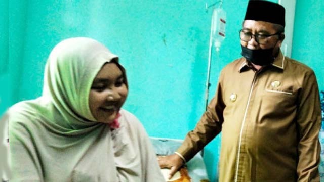 Amelia Wulandari, mahasiswi Universitas Syiah Kuala Banda Aceh yang lumpuh setelah divaksin, saat dijenguk Bupati Aceh Barat Haji Ramli MS, di RSUD Cut Nyak Dhien Meulaboh, Aceh Barat, Senin. (Foto:Antara)