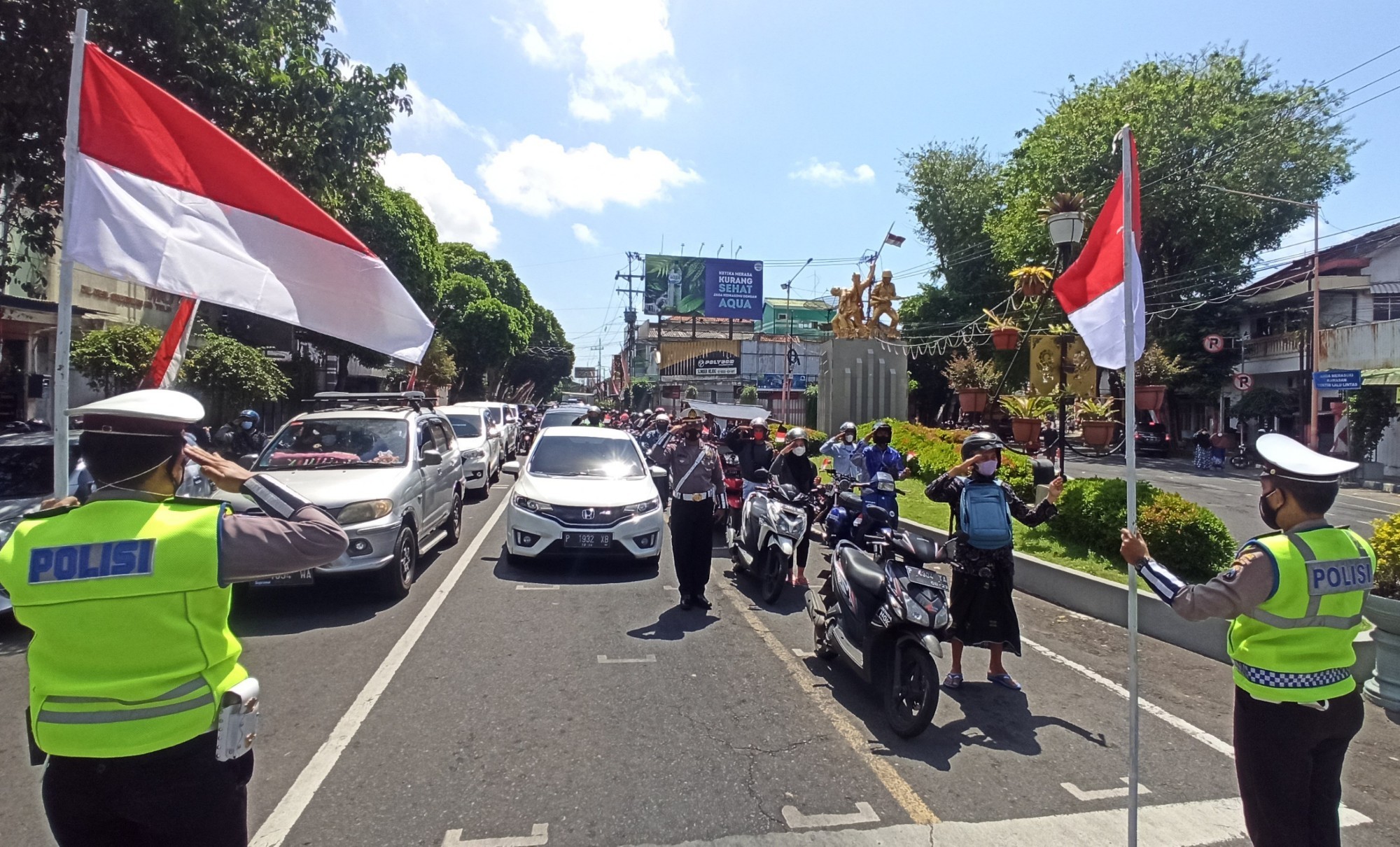 Polisi dan pengguna jalan mengambil sikap sempurna dan melakukan penghormatan kepada bendera merah putih di sekitar simpang lima Banyuwangi (foto:Muh Hujaini/Ngopibareng.id)