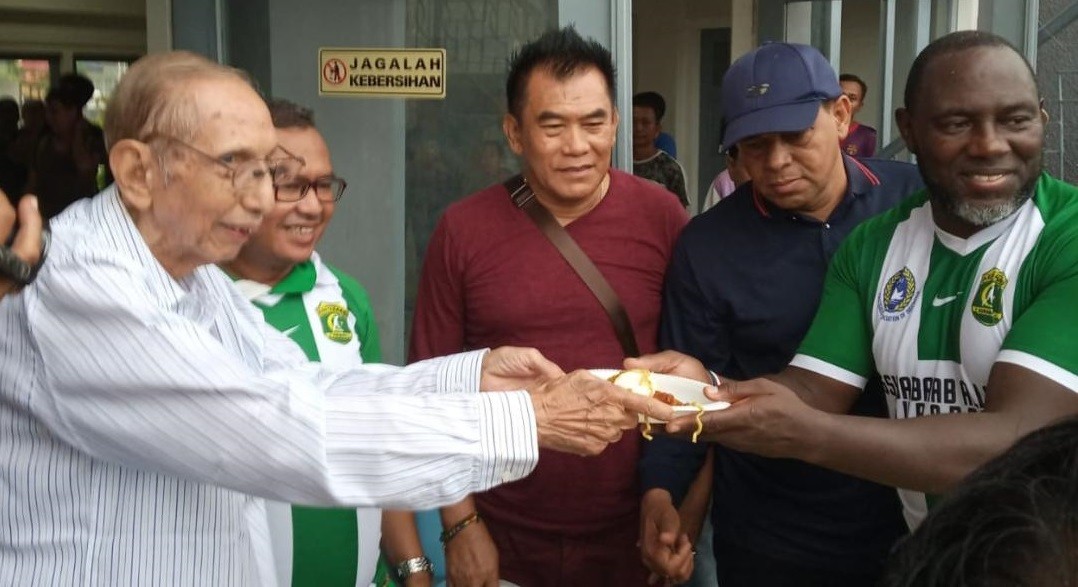 Mendiang Muhammad Barmen (Bang Moh) saat menerima potongan tumpeng dari pelatih Persipura Jacksen F. Tiago. (Foto: Istimewa)