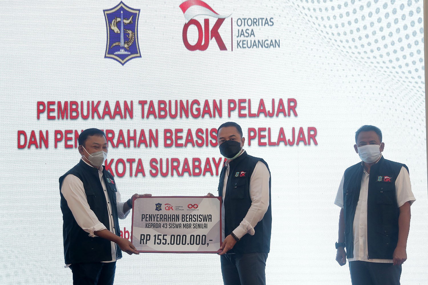 Kepala OJK Kanreg IV Jatim, Bambang Mukti Riyadi (kiri) menyerahkan beasiswa kepada Walikota Surabaya, Eri Cahyadi, di SMP Unesa 1, Surabaya, Jumat 20 Agustus 2021. (Foto: Istimewa)