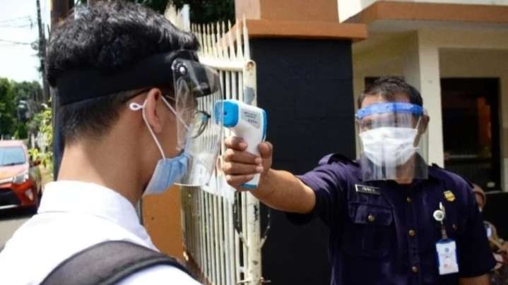 Seorang siswa diukur suhu badannya oleh petugas sekolah sebelum masuk kelas (foto: istimewa)