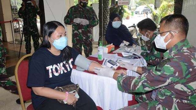 TNI lakukan vaksinasi kepada masyarakat. Ilustrasi tulisan: TNI, Garda Depan Lawan Covid-19. (Foto:Antara)
