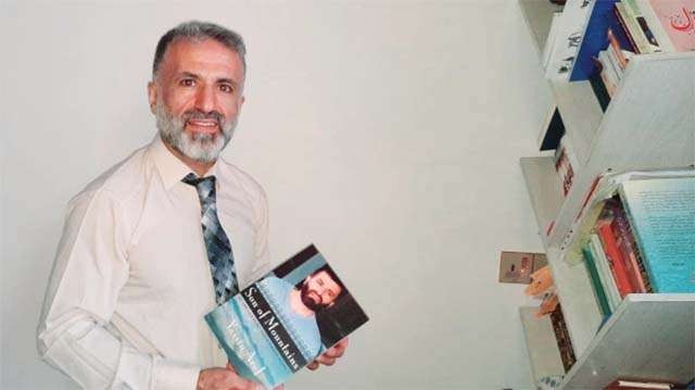 Yassin M Aref, 51 tahun,  dengan bukunya versi bahasa Inggris, Son of Mountains. (Foto: Dana Taib Menmy/Al Jazeera)