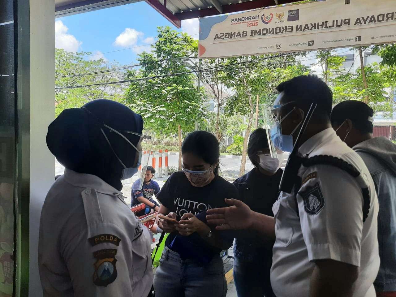 Petugas keamanan swalayan saat memeriksa QR code dari aplikasi PeduliLindungi customer. (Foto: Pita Sari/Ngopibareng.id)