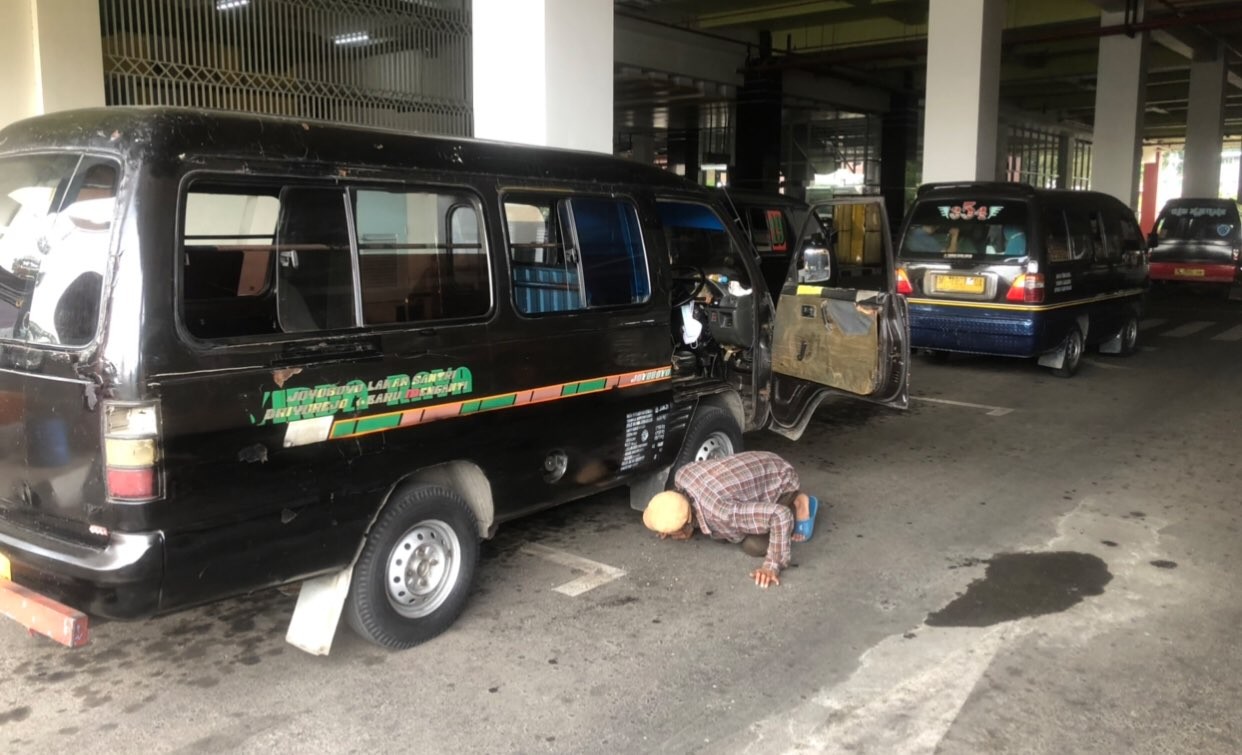 Salah satu supir angkot yang sibuk mengecek mobilnya (Foto: Andhi Dwi/Ngopibareng.id)