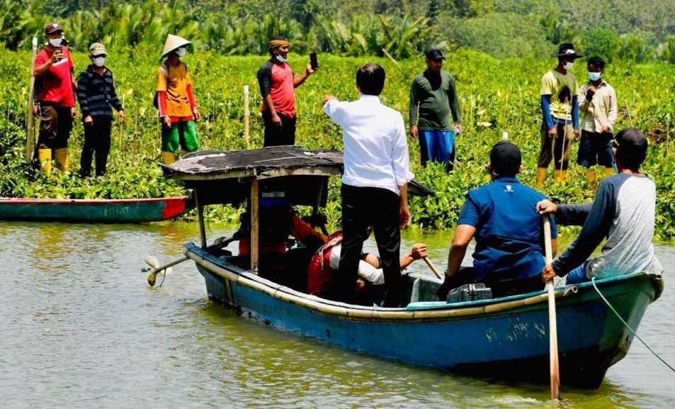 Presiden menyeberangi sungai dengan perahu, bergabung dengan masyarakat menanam pohon mangrove. (Foto: Setpres)