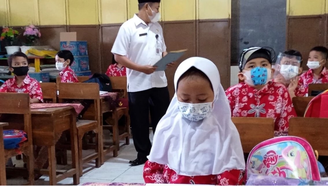 Kepala SDN Kota Kulon 1 Liwon memantau siswa yang antusias belajar memakai masker dan menjaga jarak. (Foto: Guido Saphan/Ngopibareng.id)