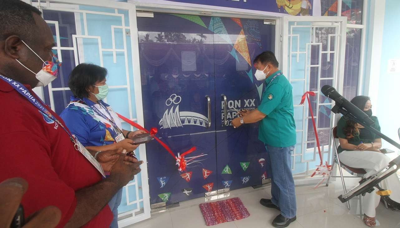 Ketua Harian PB PON Sub Mimika Marthen Paiding melakukan pemotongan pita, tanda Media Center PPM PON XX Papua resmi dibuka. (Foto: Rizal Arnas/Ngopibareng.id)