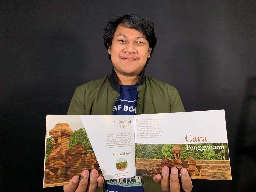 Mahasiswa Desain Komunikasi Visual (DKV) Universitas Dinamika (Undika), Rizki Maulana Ishak saat menunjukan buku mengenai Candi Tikus buatannya. (Foto: istimewa)