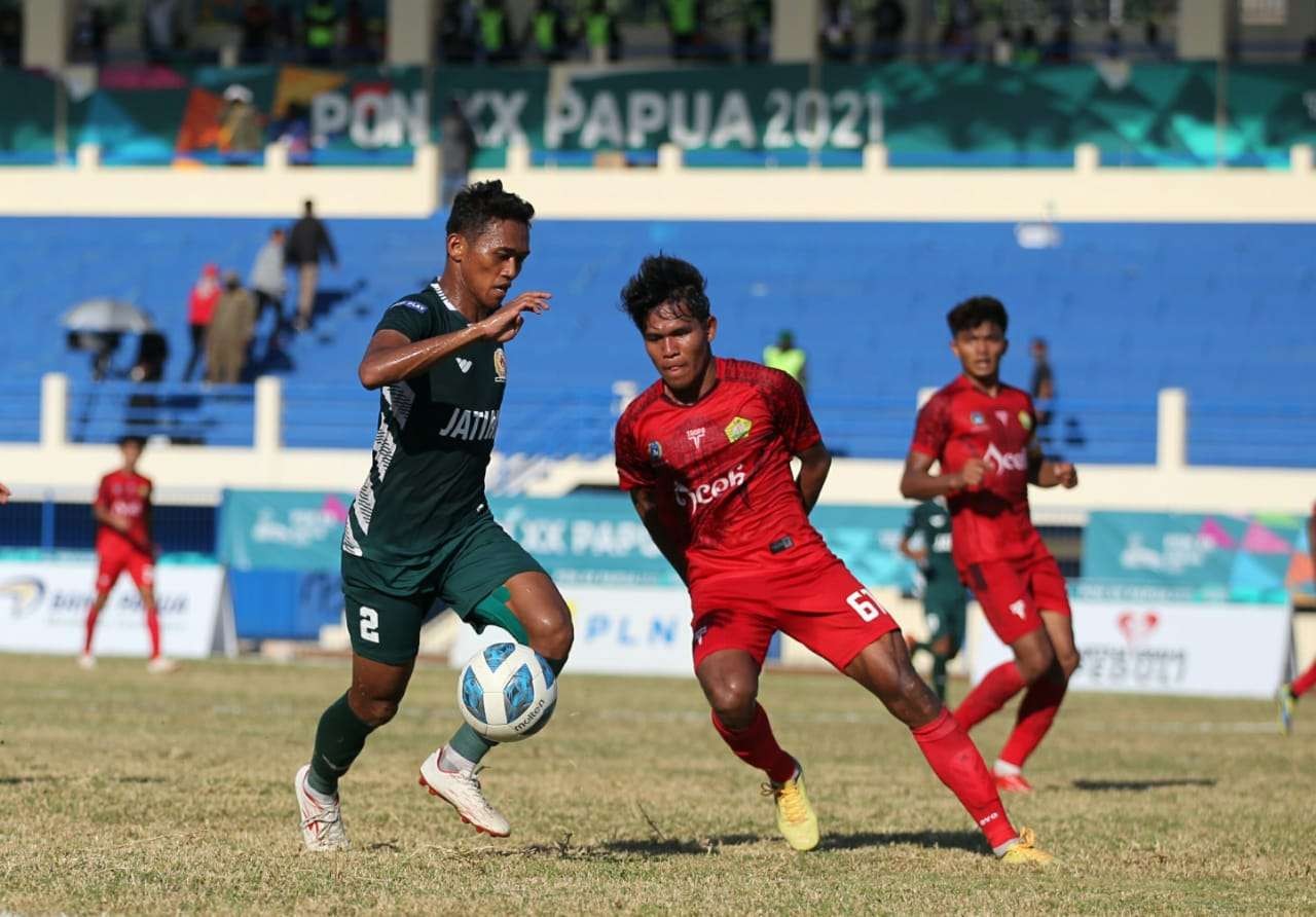 Pemain Jatim, Arif Catur Pamungkas (kiri) mencoba melewati hadangan pemain Aceh di Stadion Barnabas Youwe, Jayapura, Selasa 12 Oktober 2021. (Foto: KONI Jatim)