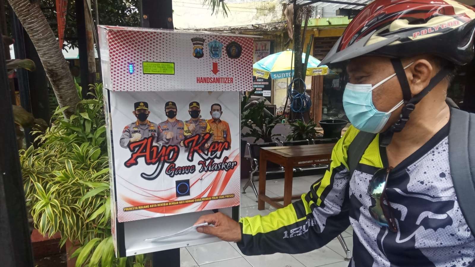 Salah satu warga Kota Malang saat menggunakan alat masker dispenser. (Foto: Lalu Theo/Ngopibareng.id)
