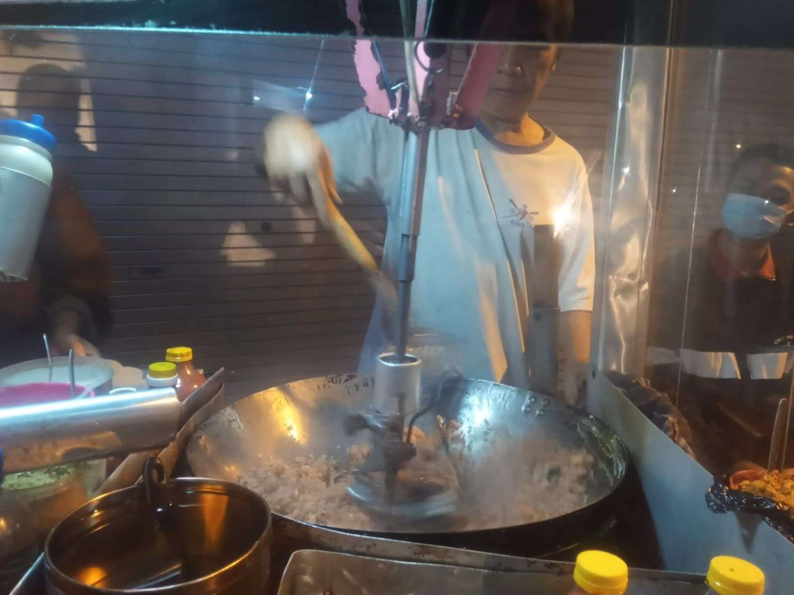 Dartadi saat mengoperasikan alat pengaduk nasi gorengnya (Foto: Lalu Theo/ngopibareng.id)