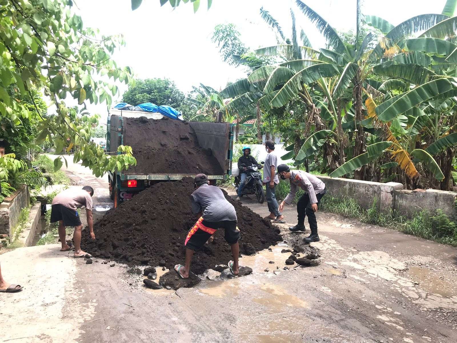 Warga dibantu anggota TNI dan Polri memperbaiki jalan rusak parah di Desa Ngepoh, Kecamatan Dringu, Kabupaten Probolinggo. (Foto: Ikhsan Mahmudi/Ngopibareng.id)