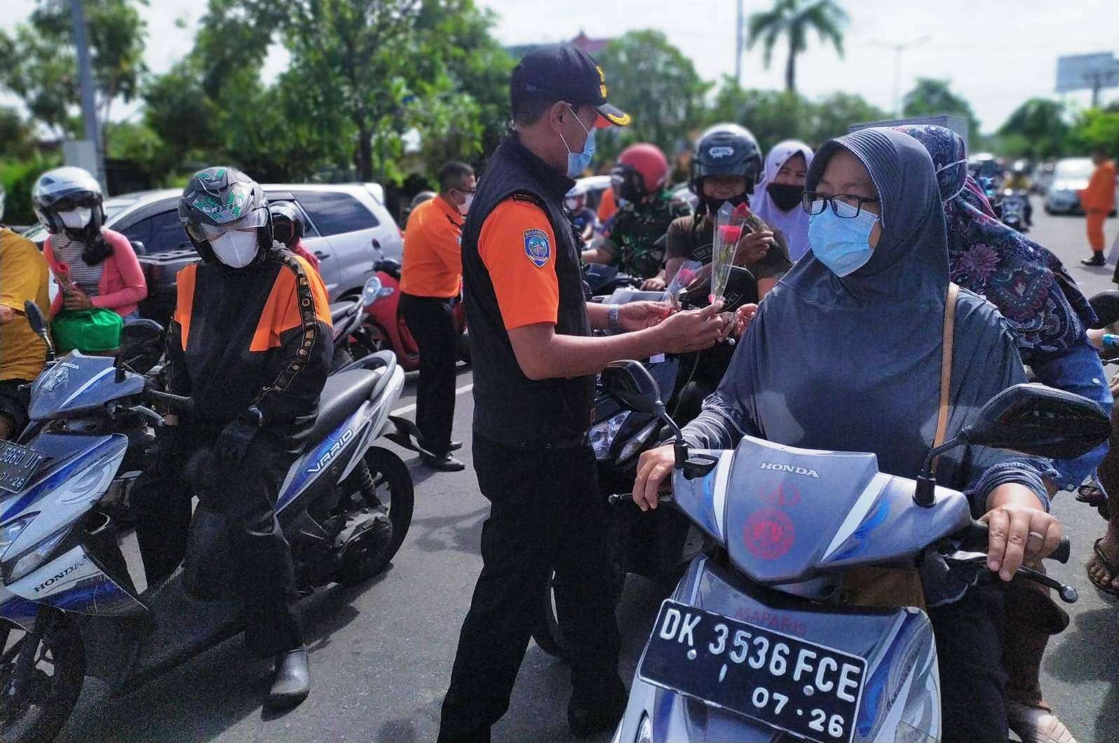 Pegawai Kantor Basarnas Bali membagikan bunga mawar yang berisi pesan pemberantasan korupsi kepada pengendara motor (foto: Basarnas Bali)