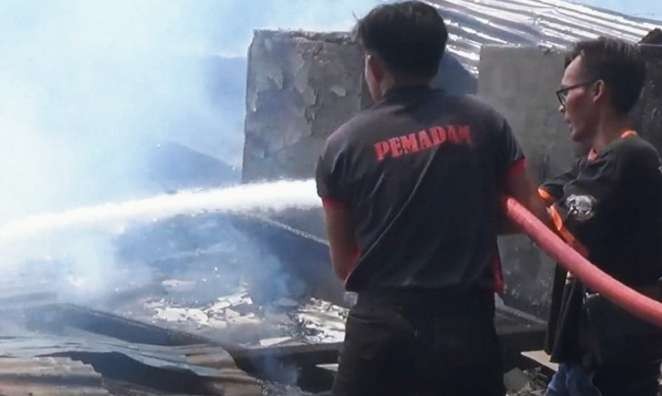 Petugas pemadam kebakaran Pemkab Bondowoso memadamkan api membakar dua rumah warga di Kelurahan Mimbaan Kecamatan Panji.(foto: BPBD Situbondo)